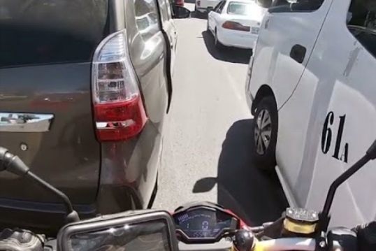 Criança pendurada na porta do carro